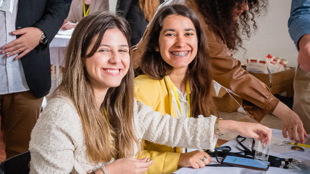 Two female students at a registration desk smiling at the camera