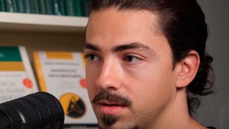 Jorge Muñoz speaks into a microphone, to a podcast guest.